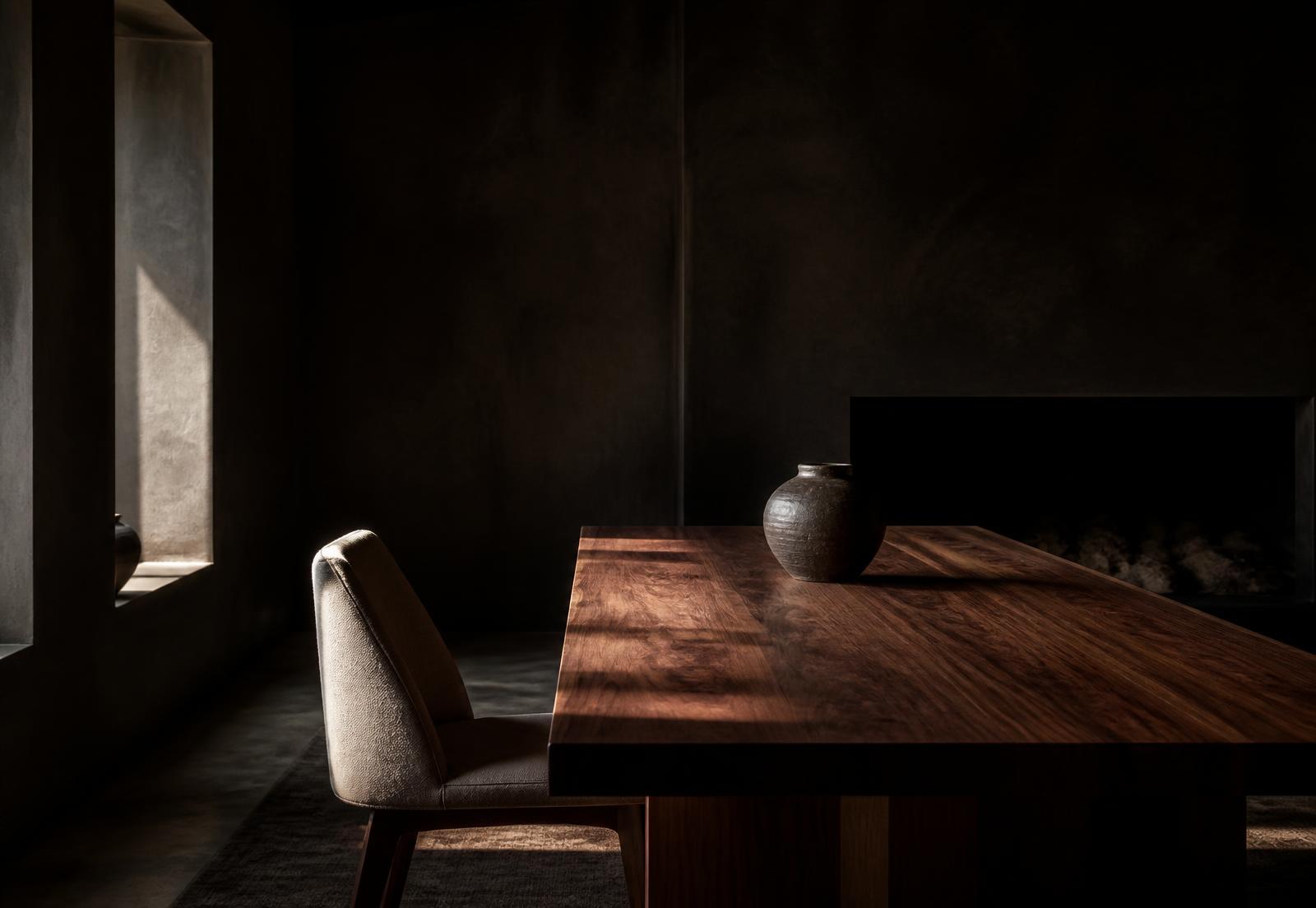 Solid walnut plank dining table in a dim, warm plaster room